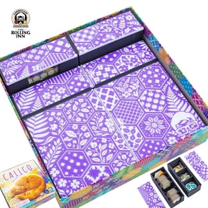 Puede incluir: Una caja de juego de mesa con un patrón floral morado y blanco. La caja está abierta, revelando compartimentos y piezas del juego. La caja del juego está etiquetada "Calico" con una ilustración de un gato.