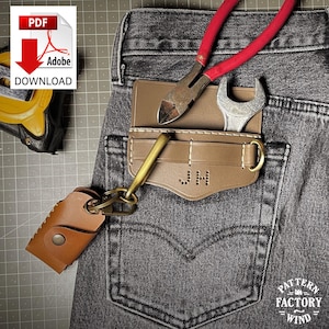 May include: A brown leather pocket organizer with the initials "JH" and a brass key holder is shown in the back pocket of a pair of gray jeans. A pair of red-handled pliers and a wrench are in the organizer. A leather key fob is attached to the key holder.