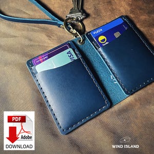 May include: A dark blue leather card holder with two slots for cards. The holder has a stitched edge and a lanyard attached. The cards in the holder are a Lotte Card and a Visa card. The text "WIND ISLAND" is visible in the bottom right corner.