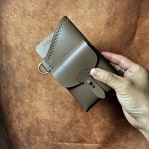 May include: A white ceramic mug with a black handle and the text "But First, Coffee" in a bold, black font. The mug is on a wooden surface. The mug is approximately 10 cm tall.