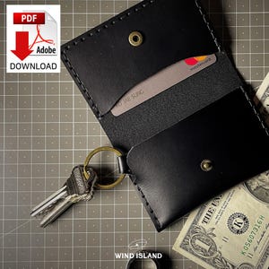 May include: Black leather wallet with a key ring and two cards inside. The cards have the names "KO JAE SUNG" and "mastercard" printed on them. The wallet has a stitched edge and a small metal button.