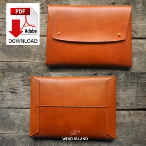 May include: A brown leather envelope-style clutch with a flap closure and two brass rivets. The clutch has a stitched seam around the edge and the text "WIND ISLAND" is printed on the bottom.