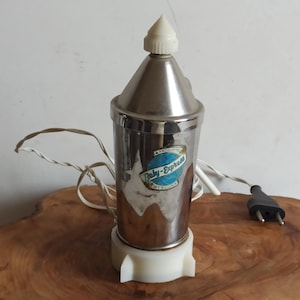 May include: Vintage Baby-Express bottle warmer. The cylindrical, stainless steel warmer has a white plastic base and a conical top. A blue and white label is on the front. A white cord and black plug are attached.