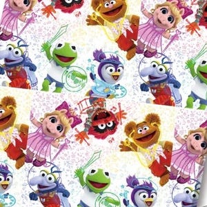 May include: A repeating pattern featuring Muppet Babies characters including Kermit, Piggy, Fozzie, Gonzo, and Animal. The colourful cartoon figures are depicted in various poses against a white background filled with small line-art musical notes and stars.
