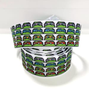 Pode incluir: Um rolo de fita gorgurão branca com um padrão repetitivo de rostos de tartarugas de desenho animado usando máscaras roxas, azuis, laranjas e vermelhas. A fita tem uma superfície texturizada e exibe os personagens em linhas horizontais.