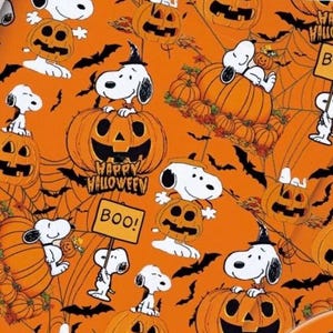 Op de afbeelding: Oranje inpakpapier met een herhalend patroon van Snoopy-figuren, pompoenen, zwarte vleermuizen en spinnenwebben. Het ontwerp bevat de tekst Happy Halloween en Boo, waarbij Snoopy een heksenhoed draagt en op pompoenen zit.