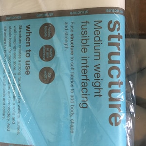Pode incluir: Um rolo de entretela fusível de peso médio branco, rotulado como "Structure". O produto tem 50.8 cm de largura e foi projetado para adicionar corpo, forma e resistência a tecidos macios. É fusível de um lado e pode ser aplicado em qualquer direção.