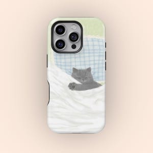 Könnte beinhalten: Handyhülle mit einem Design einer grauen Katze, die unter einer weißen Decke schläft. Der Hintergrund hat ein hellgrünes und blaues Karomuster. Die Hülle ist für ein Smartphone.