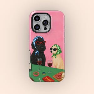 Peut inclure: Coque de téléphone rose avec une illustration de deux chiens portant des lunettes de soleil et des foulards, assis à une table avec des verres à vin, des collations et le mot "SASSY". La coque a une finition brillante et un bord surélevé pour protéger l'écran.