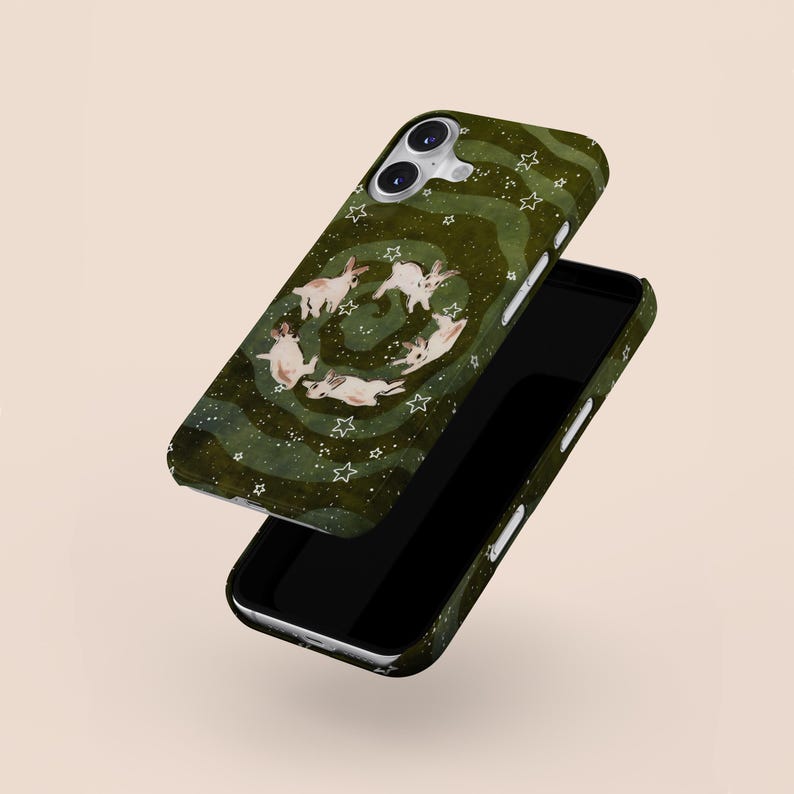 Puede incluir: Una funda de tel&eacute;fono verde con un dise&ntilde;o caprichoso de conejos blancos en c&iacute;rculo, rodeados de estrellas blancas. La funda tiene un patr&oacute;n verde ondulado y se muestra con un tel&eacute;fono negro.