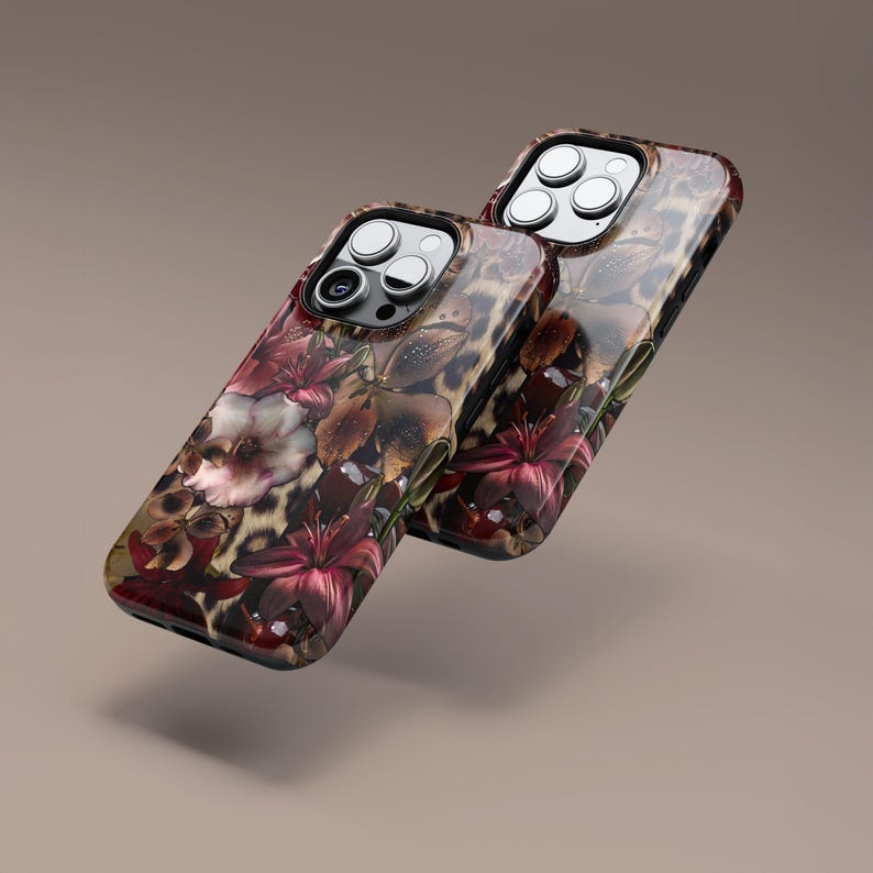 May include: Two phone cases with a floral and leopard print design. The cases feature a glossy finish with a combination of burgundy, brown, and cream colors. The floral pattern includes lilies and other flowers.