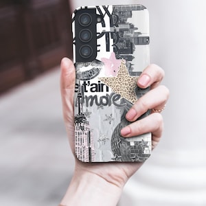 May include: A phone case with a collage design. The case features a black and white cityscape, a pink star, a leopard print star, and the word "more". The case has a camera and flash.