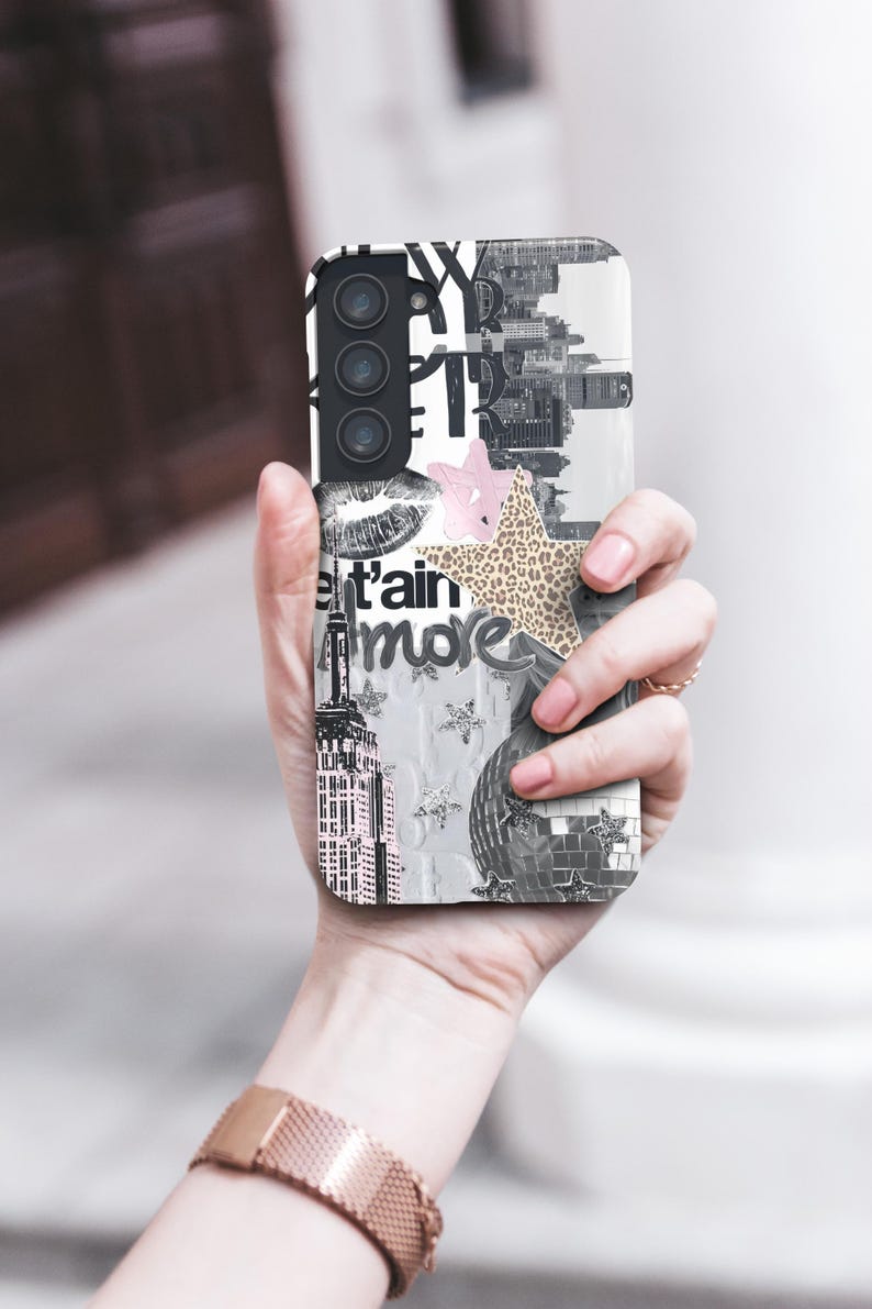 May include: A phone case with a collage design. The case features a black and white cityscape, a pink star, a leopard print star, and the word "more". The case has a camera and flash.
