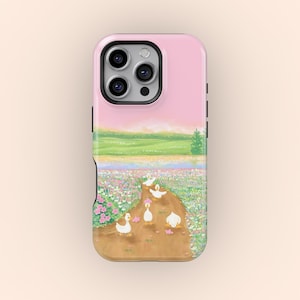 May include: A pink iPhone case depicting a rural scene with ducks on a path through a flower field. The case has a light pink sky and green hills in the background. The ducks are white with yellow beaks.