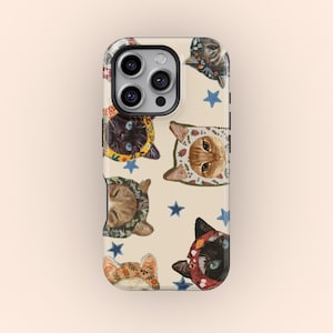 Op de afbeelding: Een telefoonhoesje met een herhaald patroon van kattengezichten met decoratieve hoeden en blauwe sterren. De katten hebben verschillende vachtkleuren en hoedontwerpen, tegen een crèmekleurige achtergrond.