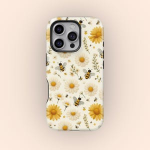 May include: A white phone case with a pattern of yellow daisies and black and yellow bees. The case has a cutout for the camera lens.