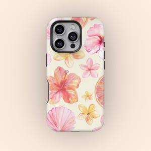 May include: A phone case with a watercolour floral design. The case features pink hibiscus flowers, yellow flowers, a seashell, and a grapefruit slice on a cream background. The case has a black camera lens and black side buttons.