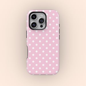 Puede incluir: Una funda de teléfono rosa con un patrón de lunares blancos. La funda tiene un borde negro y un recorte para la cámara. La funda está diseñada para un teléfono inteligente.