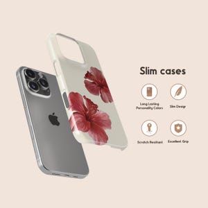 May include: A silver smartphone and a cream-colored phone case with a red hibiscus flower design. The phone case is labeled "Slim cases" and features icons for long-lasting colors, slim design, scratch resistance, and excellent grip.
