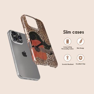 Może przedstawiać: Etui na telefon z wzorem w panterkę i czarnym kotem grającym na gitarze. Etui jest pokazane obok srebrnego telefonu. Tekst "Slim cases" jest wyświetlany po prawej stronie obrazu.
