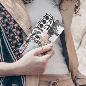 May include: A white phone case with a black and white collage design featuring the Eiffel Tower, lips, and text. Accents include a pink star and a leopard print shape. The case is held by a person.