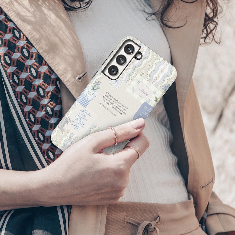 May include: A white and blue phone case with a floral design and a quote about finding beauty in everyday moments. The case has a camera lens cutout and a textured surface.