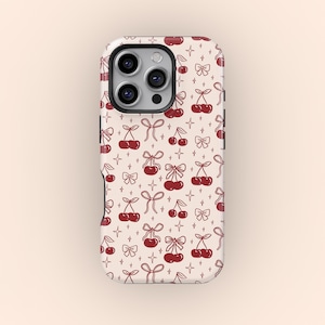 May include: A phone case with a repeating pattern of red cherries and bows on a cream background. The case has a camera cutout and buttons. The design includes small star shapes. The case is for a smartphone.