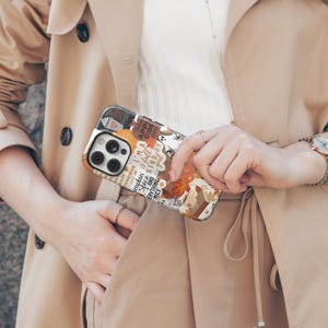 May include: A phone case with a fall-themed design. The case features a collage of autumn-inspired images and text, including pumpkins, leaves, and the phrase "I'm a fall kind of girl".