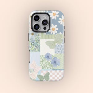 May include: A phone case with a patchwork design featuring daisies, butterflies, and floral patterns in pastel colors. The case has a light blue background with various patterned squares, creating a whimsical and artistic look.