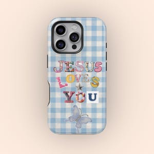 Op de afbeelding: Lichtblauwe telefoonhoes met een ruitpatroon. De hoes heeft de woorden "JESUS LOVES YOU" in kleurrijke, decoratieve letters, samen met een vlinderillustratie.