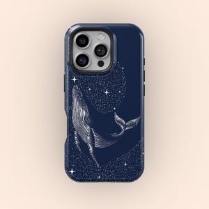 Może przedstawiać: Etui na telefon w kolorze granatowym z białą ilustracją wieloryba i wzorem nocnego nieba. Etui ma wycięcie na aparat telefonu.