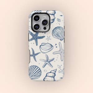 Può includere: Una custodia per telefono bianca con un motivo a conchiglie e stelle marine blu e bianche. La custodia ha un ritaglio per la fotocamera e uno sfondo bianco.