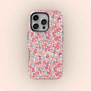 Puede incluir: Funda de teléfono con un diseño floral de pequeñas flores rosas y rojas y hojas verdes sobre un fondo crema. Tiene un borde negro y un recorte para la cámara.