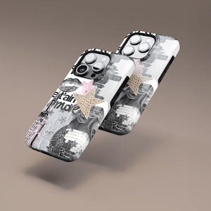 May include: Two phone cases with a monochrome design featuring a disco ball, Eiffel Tower, and text. One case has a pink flower and a leopard print star. The other case has a leopard print star. The cases have a black border.