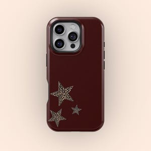May include: A burgundy phone case with three leopard print stars. The case has a smooth, matte finish and a raised edge around the camera lenses.