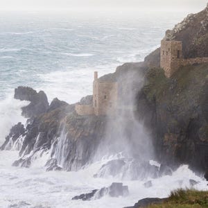 Puede incluir: Una taza de cerámica blanca con un asa negra y el texto "But First, Coffee" en negrita negra. La taza se encuentra sobre un fondo borroso, sugiriendo un ambiente acogedor.