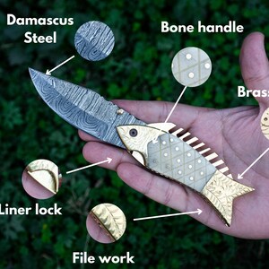 May include: A folding knife with a Damascus steel blade, bone handle, and brass bolster. The handle is decorated with a fish design and has a liner lock. The blade has a file work pattern.