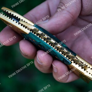 May include: A green and gold pocket knife with a decorative handle. The knife is open and the blade is visible.