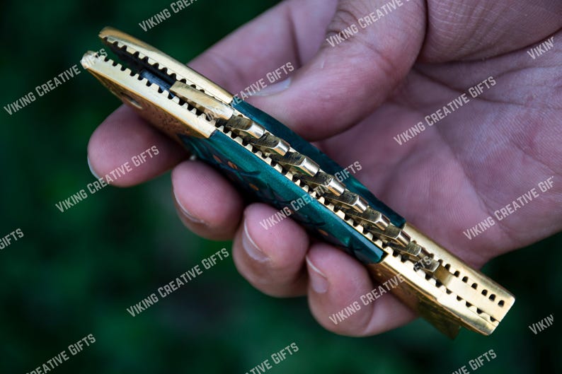 May include: A green and gold pocket knife with a decorative handle. The knife is open and the blade is visible.