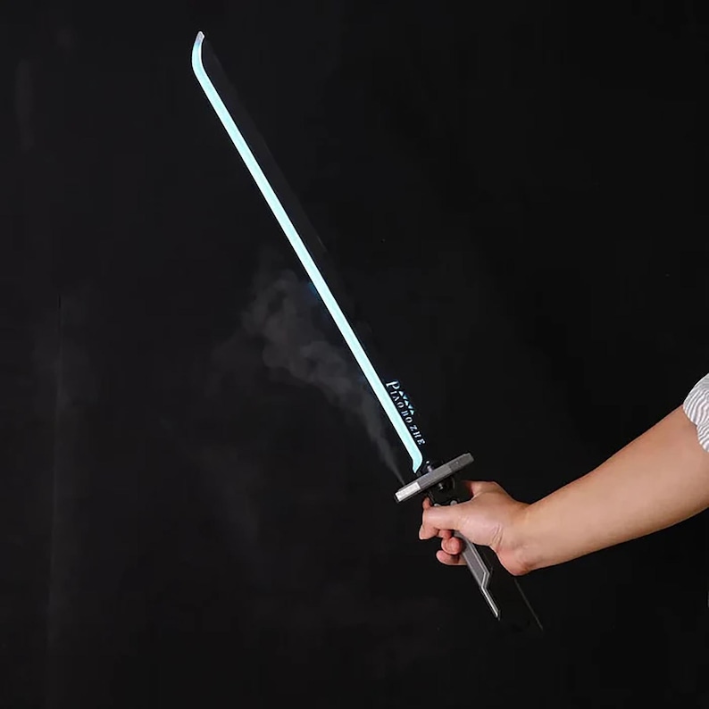 May include: A black and silver toy sword with a glowing blue blade. The sword is held in a hand against a dark background. The text "PROTOTYPE" is printed on the blade.