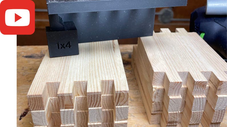 May include: Two stacks of wooden pieces with intricate interlocking joints. The pieces are arranged in a staggered pattern, creating a visually appealing design. A black jig with the label "1x4" is visible above the stacks.