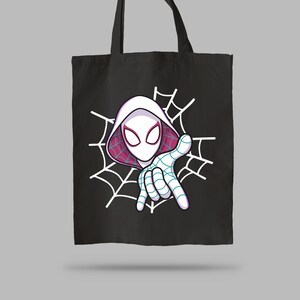 Pu&ograve; includere: Una borsa tote nera con un'illustrazione grafica di un personaggio che indossa un cappuccio e una maschera bianchi con accenti rosa. Il personaggio &egrave; posizionato davanti a un disegno di ragnatela bianca e protende una mano a ragnatela.
