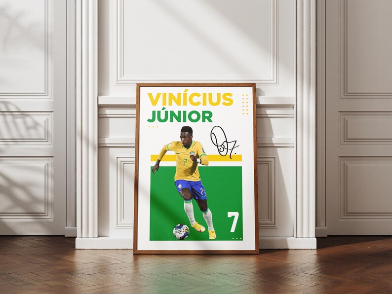 May include: A framed poster featuring soccer player Vin&iacute;cius J&uacute;nior in a yellow and blue uniform, dribbling a soccer ball. The poster includes his name, signature, and the number 7. The background is white and green.