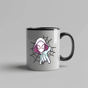 Pu&ograve; includere: Una tazza in ceramica bianca con manico e bordo neri, caratterizzata da una grafica di un personaggio con cappuccio bianco, grandi occhi e una maschera con motivo a ragnatela, su uno sfondo di ragnatela nera con fodera rosa nel cappuccio.