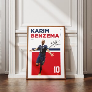 Puede incluir: P&oacute;ster enmarcado de Karim Benzema con uniforme azul, n&uacute;mero 10. El p&oacute;ster tiene un fondo rojo y blanco con el nombre y la firma del jugador. El p&oacute;ster se exhibe sobre un suelo de madera.