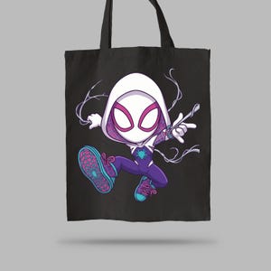 May include: A black tote bag featuring a graphic illustration of a stylized character in a white hooded suit with pink eye lenses, a purple bodysuit, and blue sneakers, depicted in a dynamic pose with white web-like lines extending from the hands.