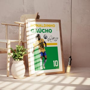 May include: A framed poster featuring a soccer player in a yellow and blue uniform, with the name "RONALDINHO GA&Uacute;CHO" in yellow and green text. The number "10" is displayed in green. A signature is also visible.