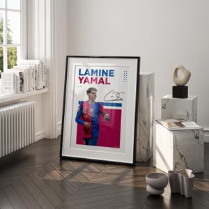 May include: Framed poster featuring Lamine Yamal in a Barcelona jersey, with his name in blue and red text. The poster includes an autograph and is displayed on a wooden floor, leaning against a white marble block.