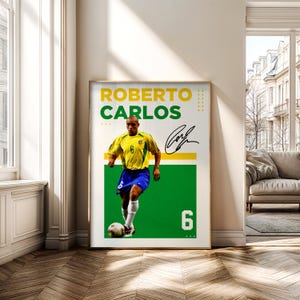 May include: Framed poster featuring Roberto Carlos in a yellow and blue soccer uniform, with the number 6. The poster has the name "ROBERTO CARLOS" in yellow and green text, along with his signature. The background is green and white.