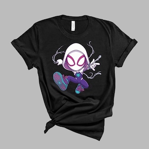 May include: A black short-sleeve t-shirt featuring a graphic of a cartoon character wearing a white hood, a purple and white suit with a teal spider emblem, and teal sneakers with pink laces, depicted in a dynamic pose with white web-like lines.